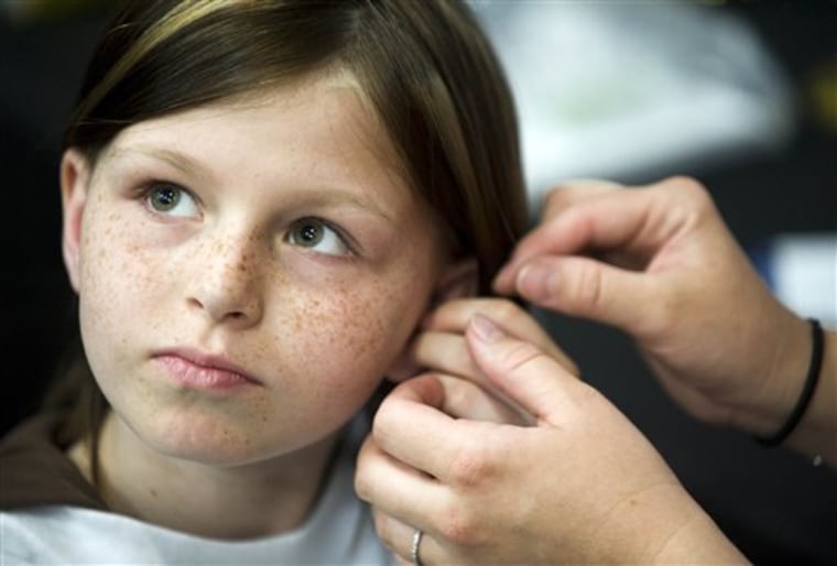 This May photo shows Zahra Clare Baker, 10, getting a hearing aid at an event Charlotte Motor Speedway. 